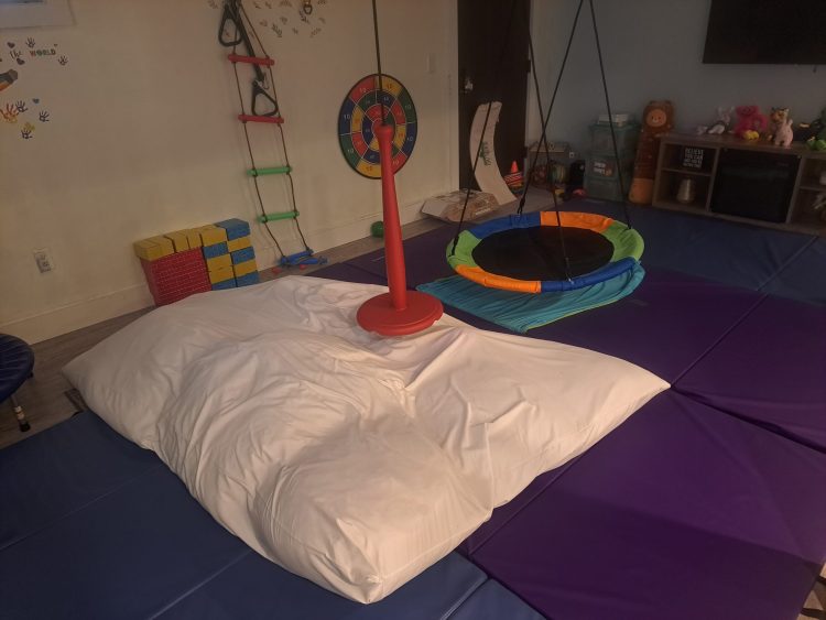 Colorful sensory room with rainbow trampoline and climbing equipment